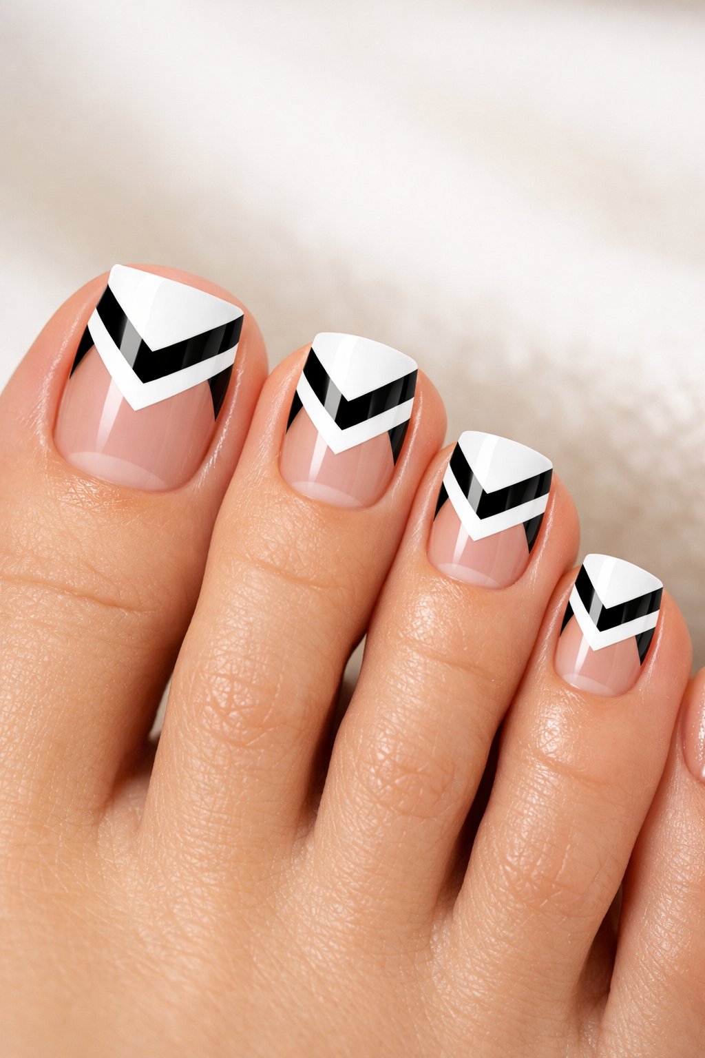 Close-up of toes with black and white chevron patterned French tip nail designs.