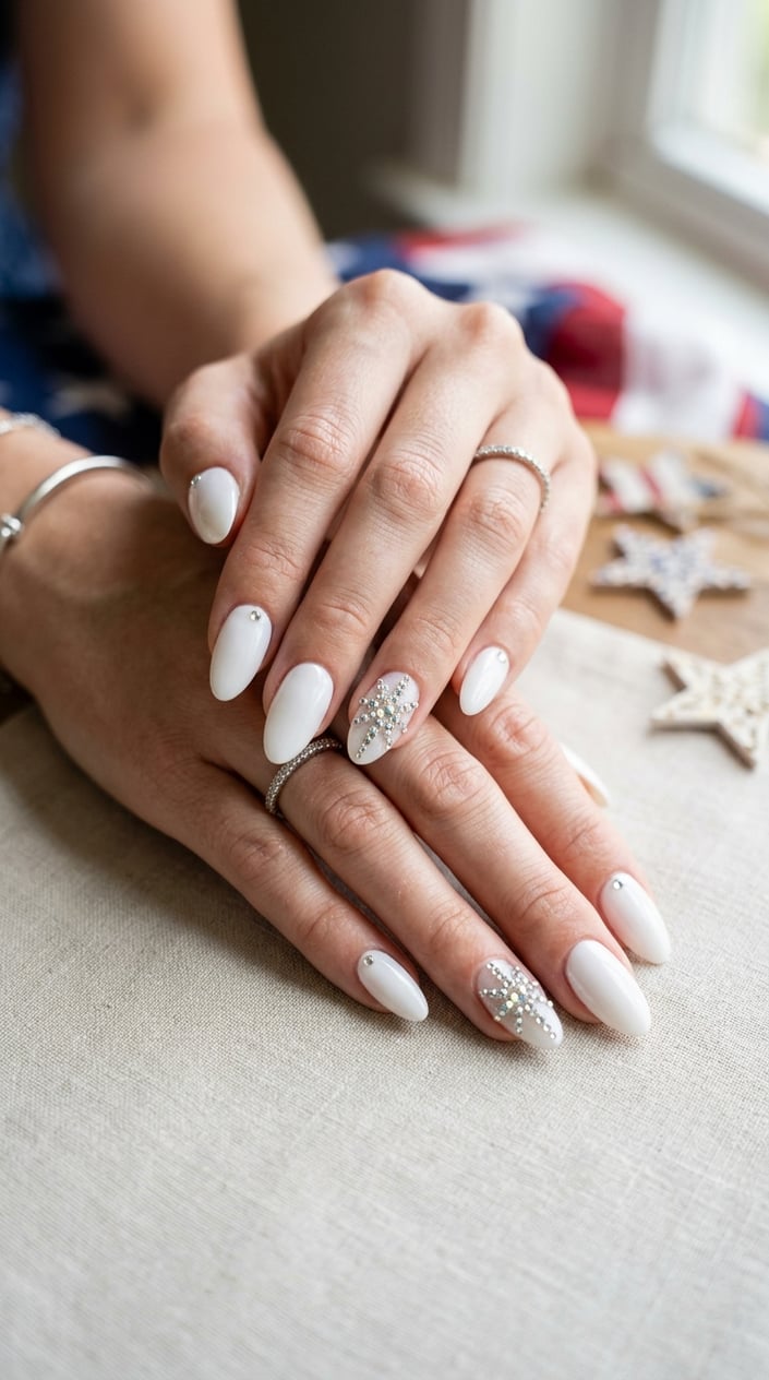 Close-up of hands with white almond-shaped nails decorated with rhinestone starburst designs.